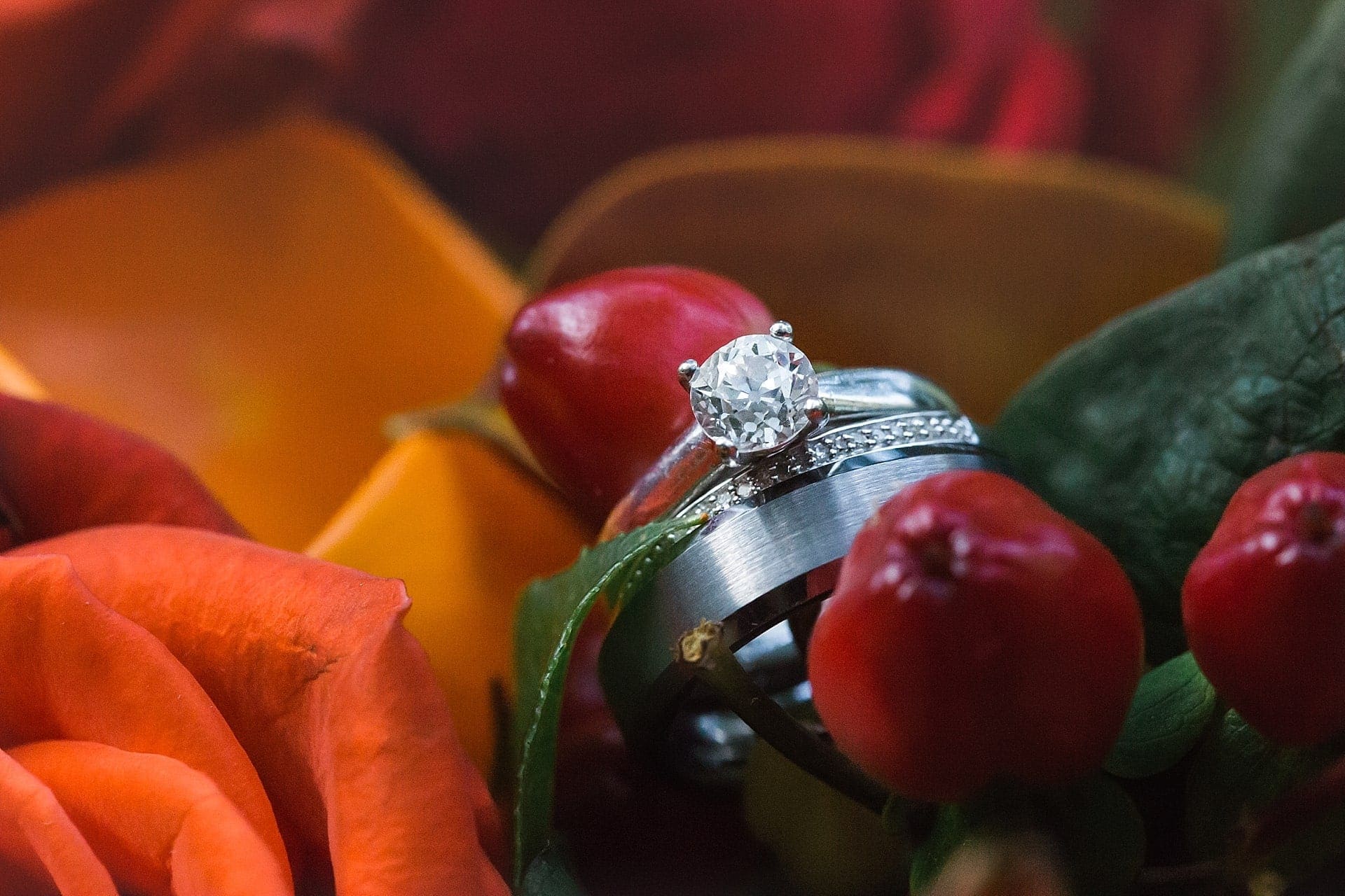 Close up of wedding ring and engagement ring in a fall arrangement of flowers and berries